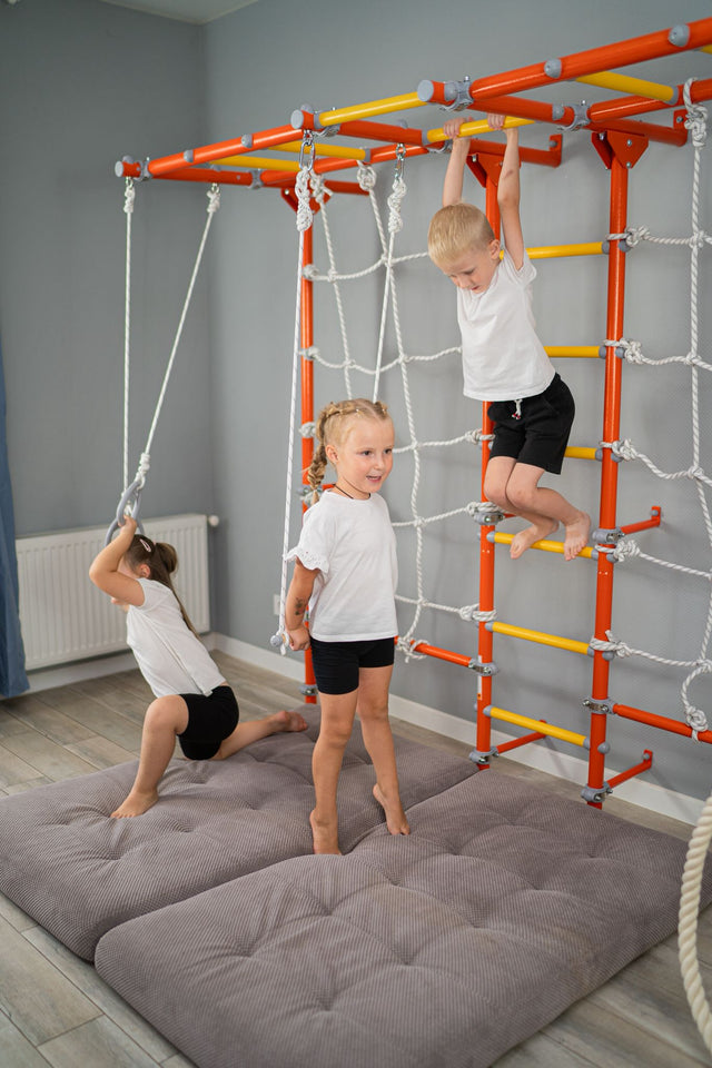 Three kids playing on a professionally built steel indoor play gym with safety mats