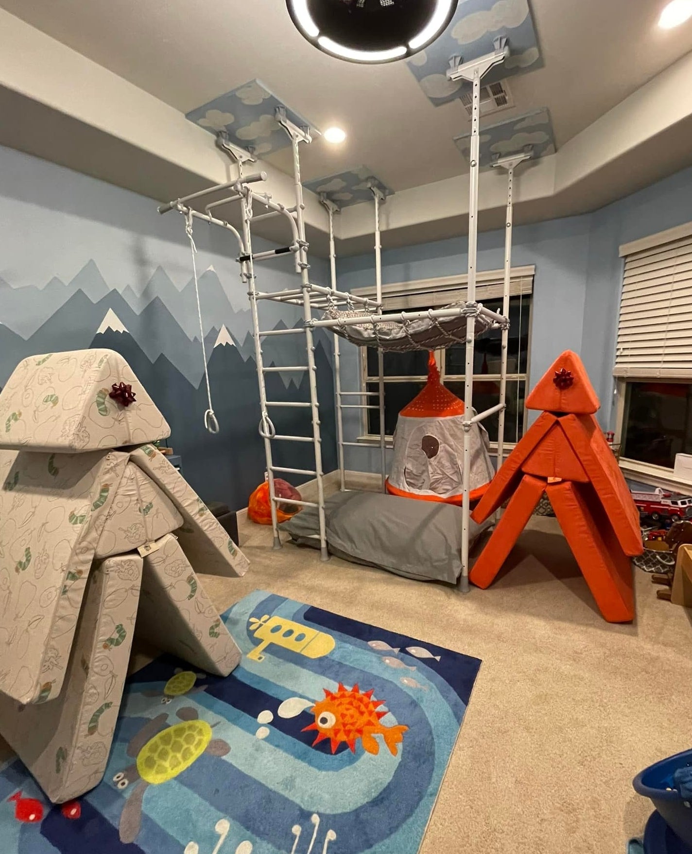Real sensory playroom with a Brainrich play gym, hanging nest swing, play tent, and foam climbing forts with gift bows