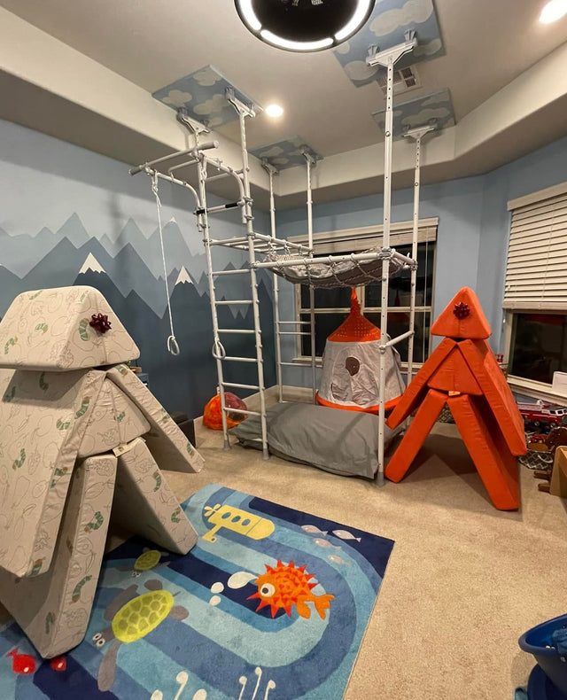Real sensory playroom with a Brainrich play gym, hanging nest swing, play tent, and foam climbing forts with gift bows