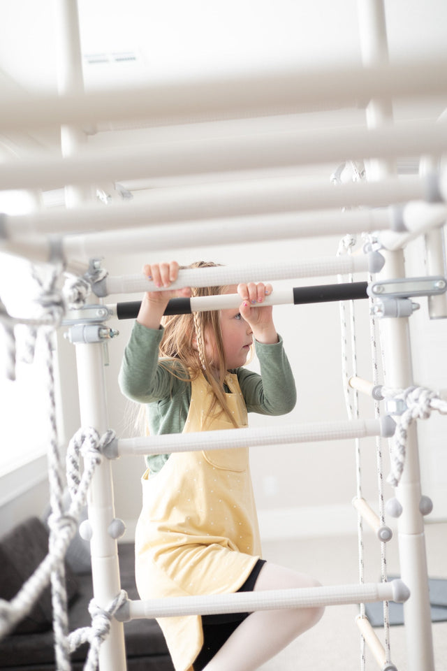 A girl pulls her chin over the pull-up bar of a Brainrich indoor gym