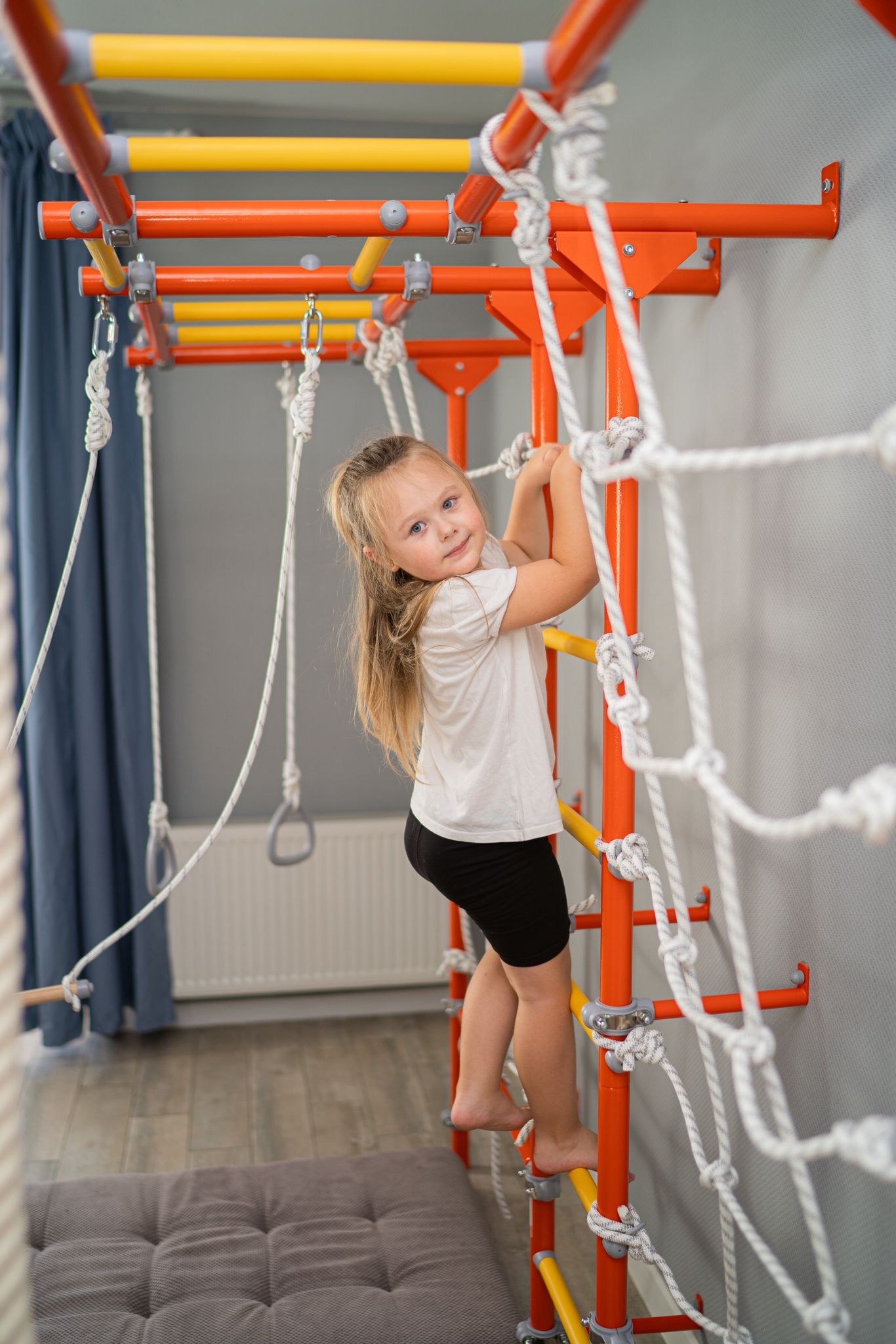 Girl climbing calmly on a Brainrich wall-mounted play gym during a quiet homeschool reset