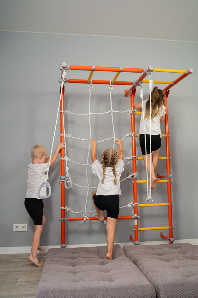 Three kids learning through movement, climbing the net and ladders of a wall-mounted Brainrich play gym