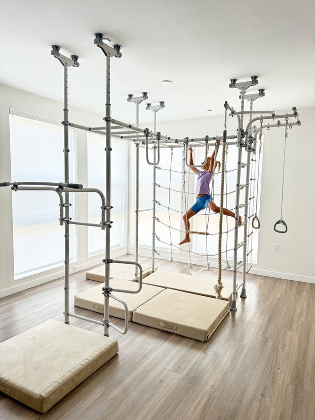 Girl joyfully swinging mid-air on a Brainrich indoor play gym, a safe outlet for movement stimming
