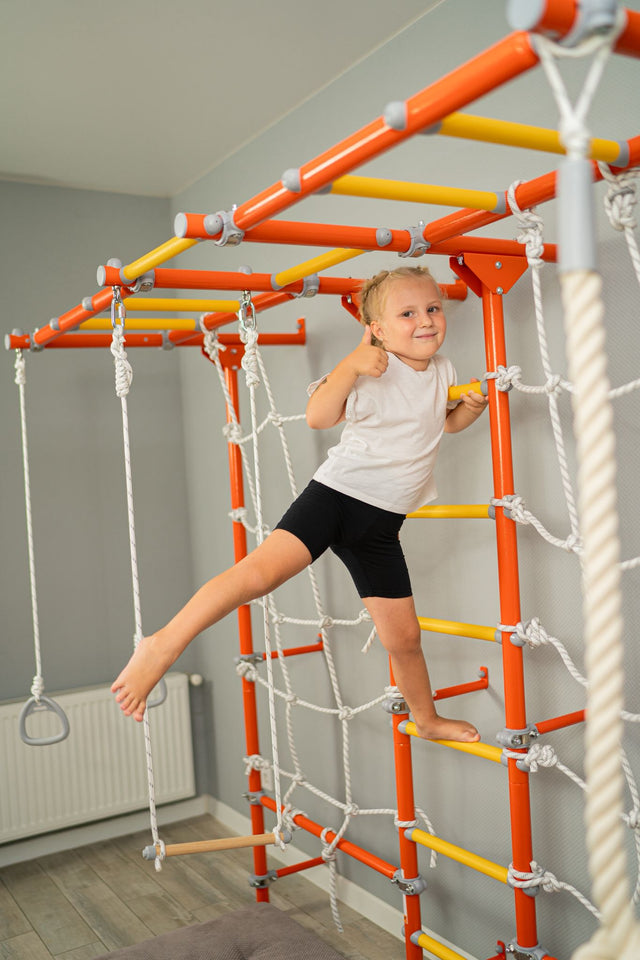 Girl climbing a steel Brainrich wall-mounted play gym with climbing net and monkey bars