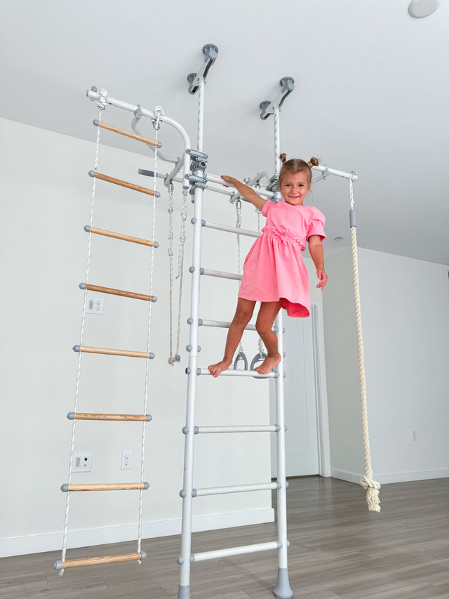 Girl climbing a Brainrich floor-to-ceiling play gym at home in Canada