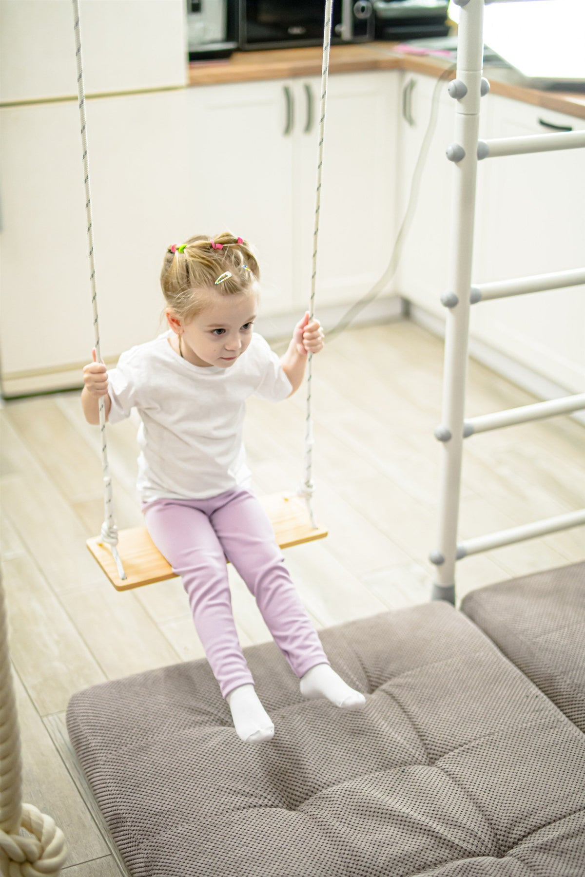 Toddler on a swing hung from the monkey bar span of a Brainrich play gym
