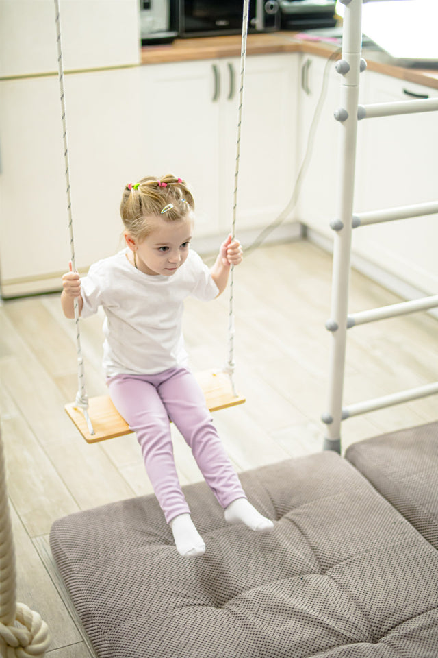 Toddler on a swing hung from the monkey bar span of a Brainrich play gym