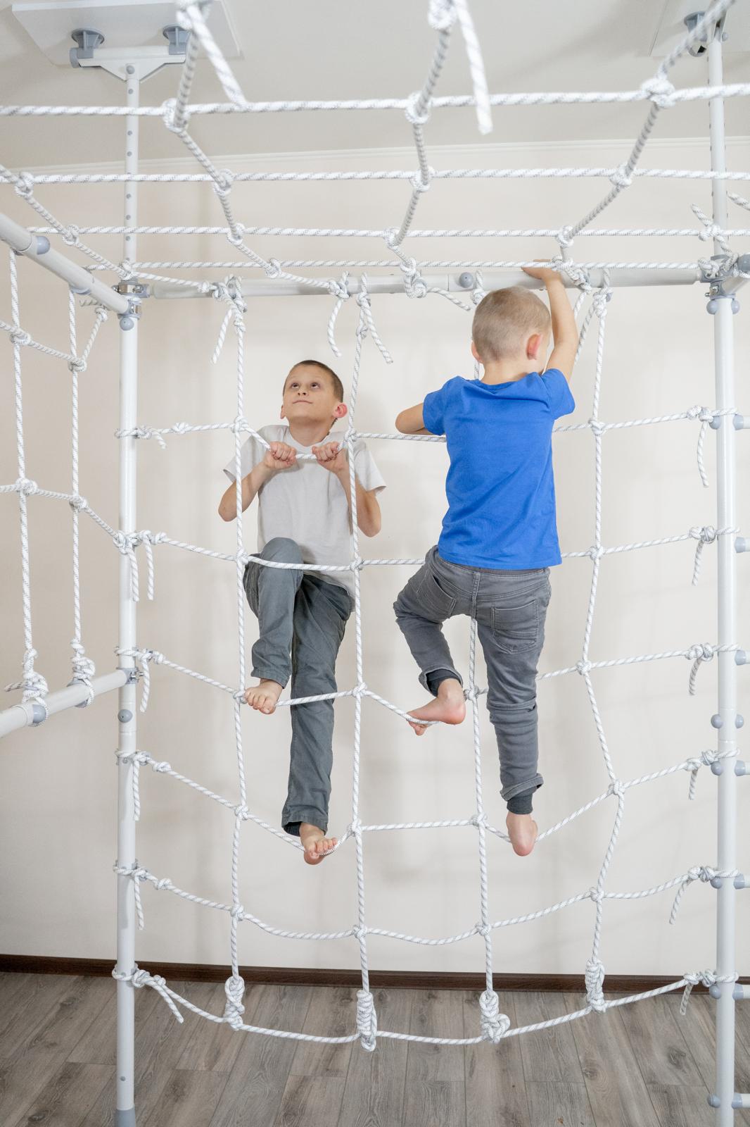 Two kids climbing the net of a Brainrich indoor gym instead of watching screens