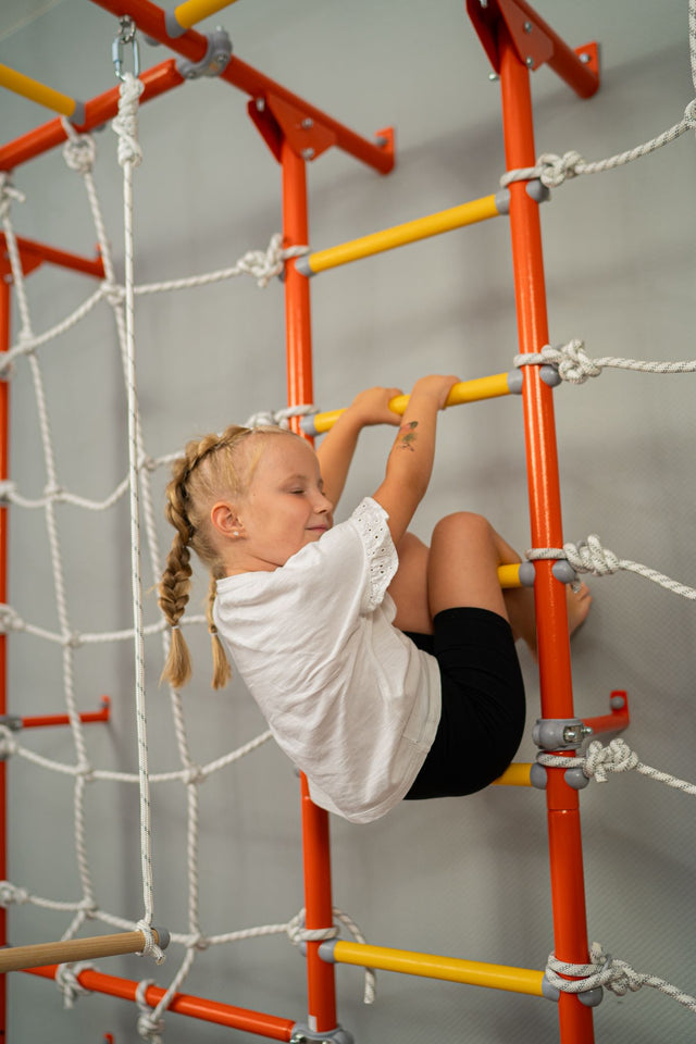 Girl climbing a Brainrich play gym ladder with focus, the kind of daily practice a homeschool PE log records