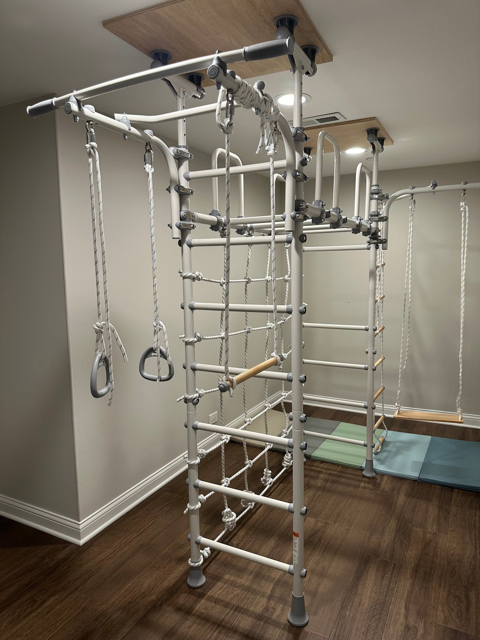 A Brainrich play gym set up in a real family's basement room with a cozy reading corner, the one movement-zone splurge in a budget homeschool room
