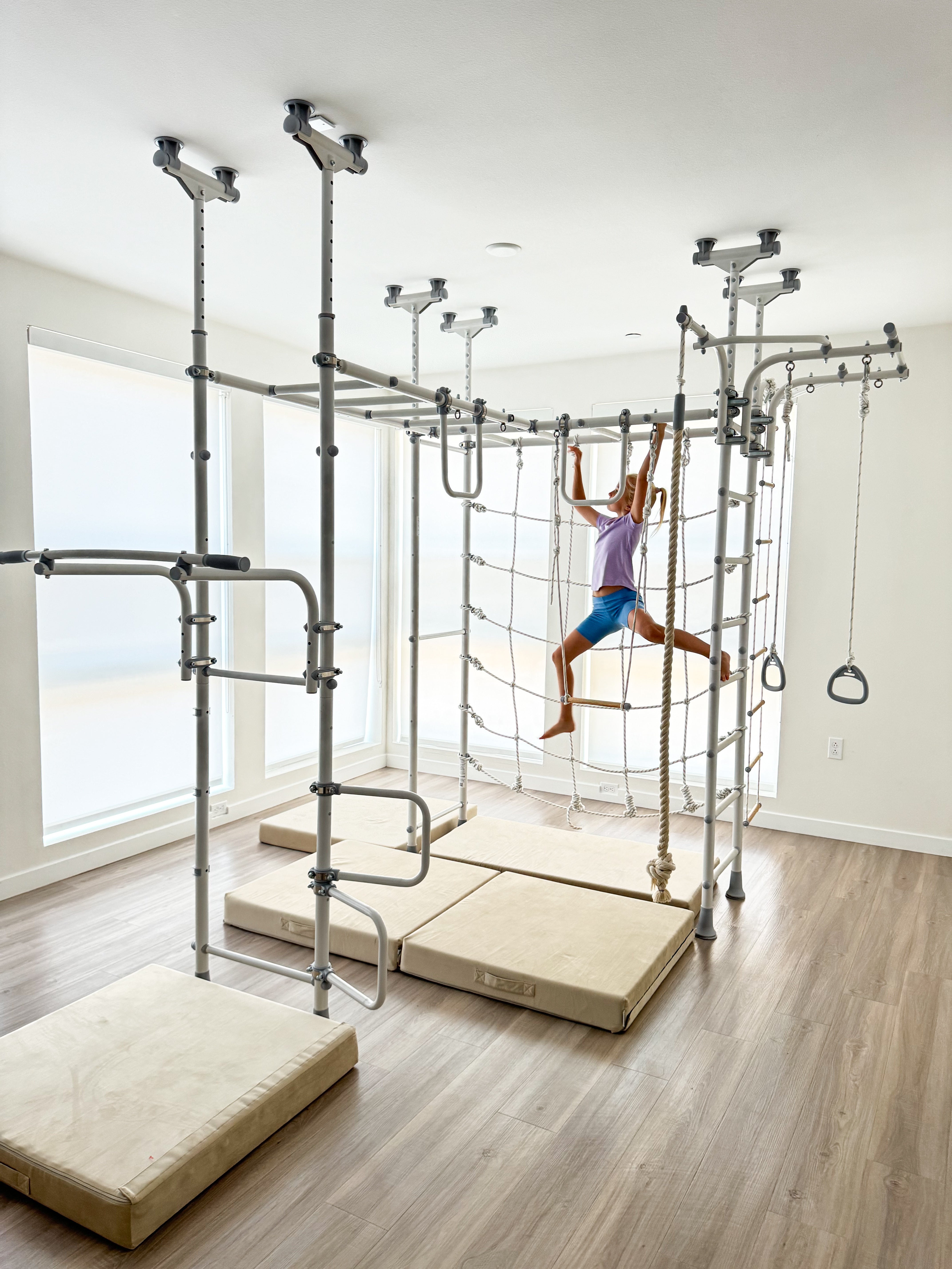Girl joyfully swinging mid-air on a Brainrich indoor play gym, a safe outlet for movement stimming