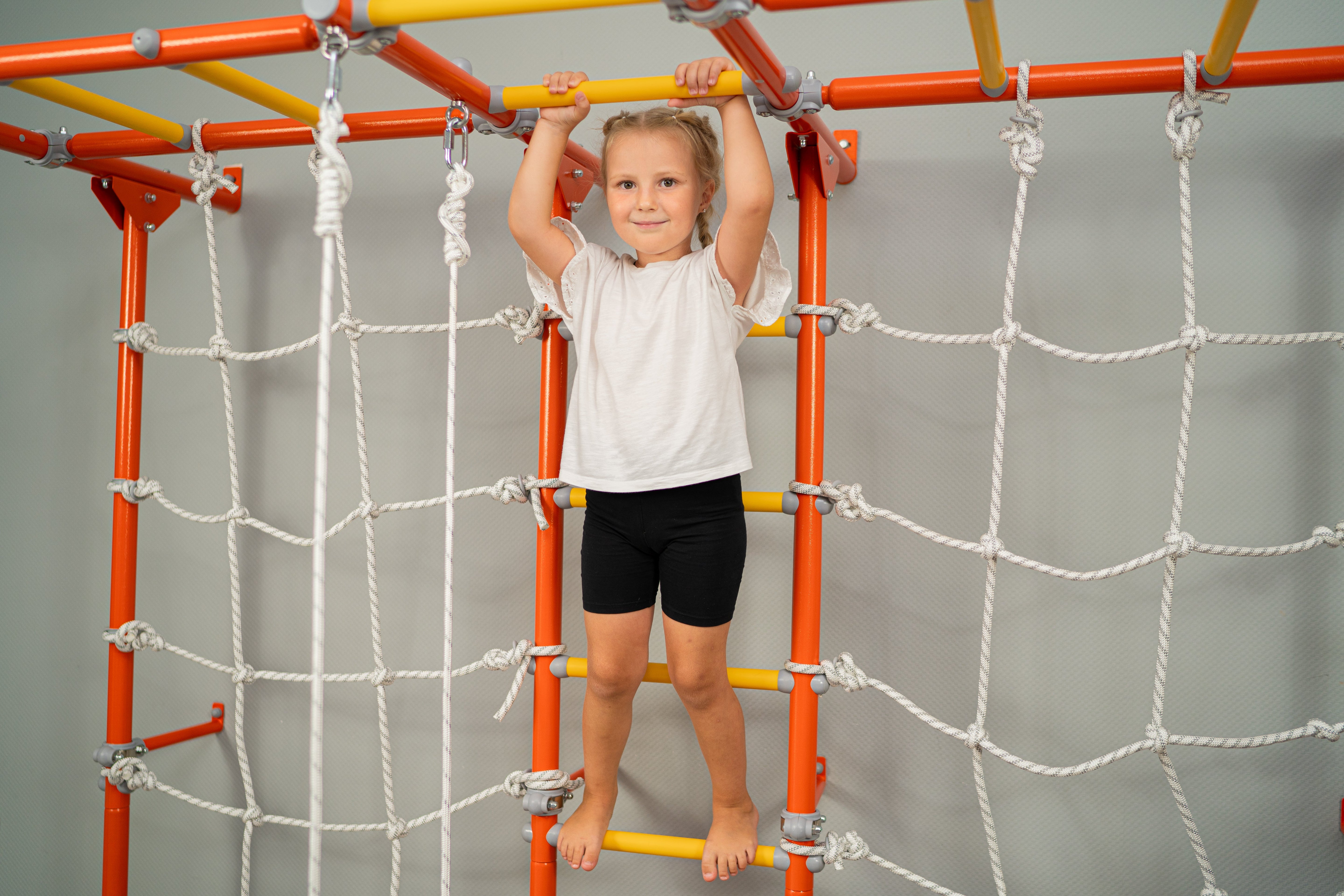 Toddlers and mom playing in wal-mounted play gym
