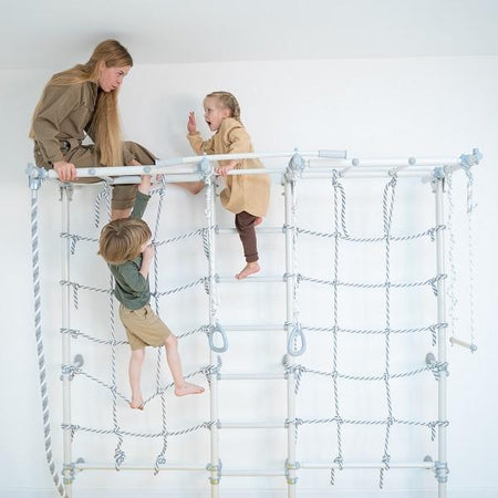 Toddlers and mom playing in wal-mounted play gym